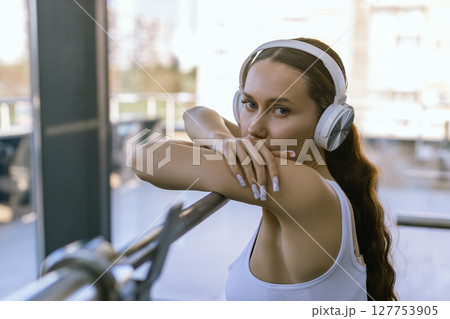 Sexy girl wearing sportswear is posing next smith machine in the fitness center. Sexy girl wearing sportswear is posing next smith machine in the fitness center. 127753905