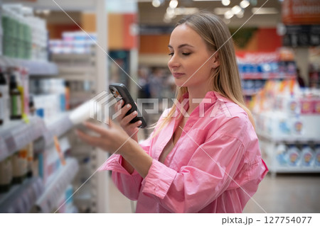 Customer using smartphone scanning products in supermarket Customer using smartphone scanning products in supermarket 127754077