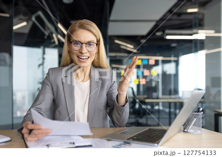 A professional woman, wearing glasses, expresses herself during a meeting or a presentation. A professional woman, wearing glasses, expresses herself during a meeting or a presentation. 127754133