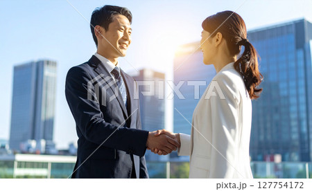 握手をするスーツを着た男女（AI生成画像） 127754172