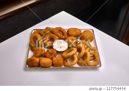 Fried appetizer platter with onion rings and sauce Fried appetizer platter with onion rings and sauce 127754434
