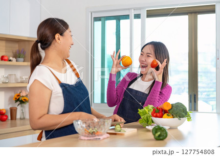 Healthy Lifestyle and Fun Cooking. Two women sharing laughter while cooking with fruits and vegetables. 127754808