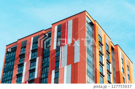 Tall, modern condominium building with glass windows and a sleek exterior. High-rise residential 127755037