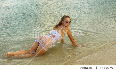 The sunburnt woman tourist spends her vacation. Sexy playful young lady dancing and posing in the water of the sea The sunburnt woman tourist spends her vacation. Sexy playful young lady dancing and posing in the water of the sea 127755079