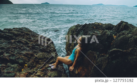 Woman meditates, relaxes on rock crack reef hill in stormy morning cloudy sea. Concept feminine, sexual vaginal health, womanly, freedom, freshness Woman meditates, relaxes on rock crack reef hill in stormy morning cloudy sea. Concept feminine, sexual vaginal health, womanly, freedom, freshness 127755192