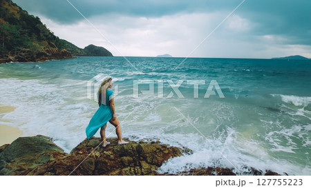 Woman meditates, relaxes on a rock reef hill in stormy morning rain cloudy sea. Concept feminine, relax, sexual health. Dark dramatic silhouette view Woman meditates, relaxes on a rock reef hill in stormy morning rain cloudy sea. Concept feminine, relax, sexual health. Dark dramatic silhouette view 127755223