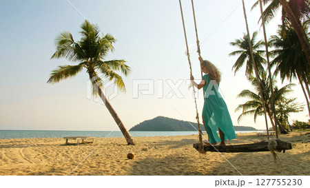 Seductive woman swinging on a swing on a tropical beach, on shores of the turquoise sea. Concept travel, walks, rest in sea, tropical resort coastline relaxation traveling tourism summer holidays. Seductive woman swinging on a swing on a tropical beach, on shores of the turquoise sea. Concept travel, walks, rest in sea, tropical resort coastline relaxation traveling tourism summer holidays. 127755230