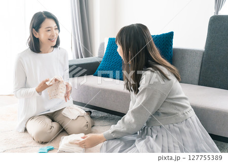 出産準備をしながら明るい未来の話をする母と娘 127755389