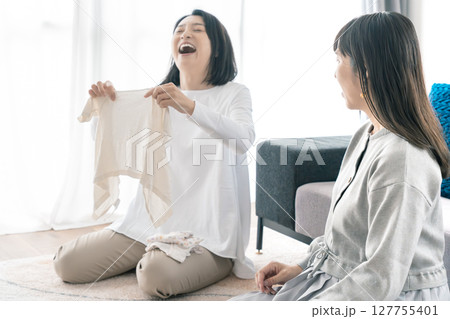 出産準備をしながら明るい未来の話をする母と娘 127755401