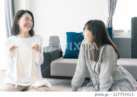 出産準備をしながら明るい未来の話をする母と娘 127755413