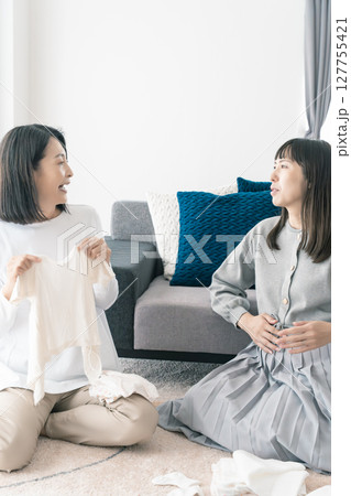 出産準備をしながら明るい未来の話をする母と娘 127755421