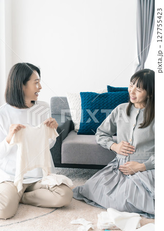 出産準備をしながら明るい未来の話をする母と娘 127755423
