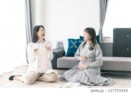 出産準備をしながら明るい未来の話をする母と娘 127755429