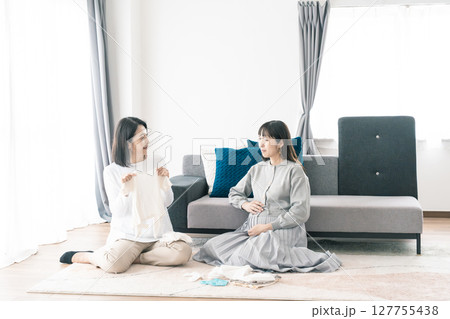 出産準備をしながら明るい未来の話をする母と娘 127755438