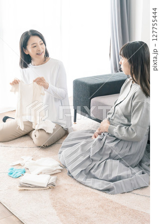 出産準備をしながら明るい未来の話をする母と娘 127755444