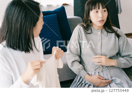 出産準備をしながら明るい未来の話をする母と娘 127755449