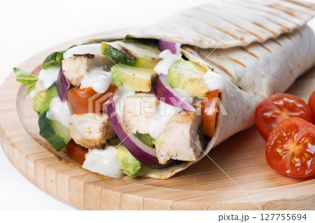 A delicious grilled chicken wrap with vegetables and avocado 127755694