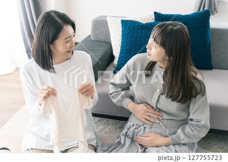 出産準備をしながら明るい未来の話をする母と娘 127755723