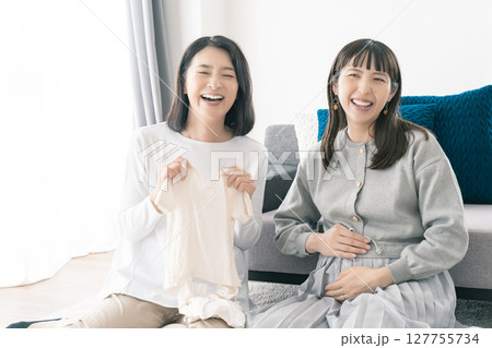 出産準備をしながら明るい未来の話をする母と娘 127755734