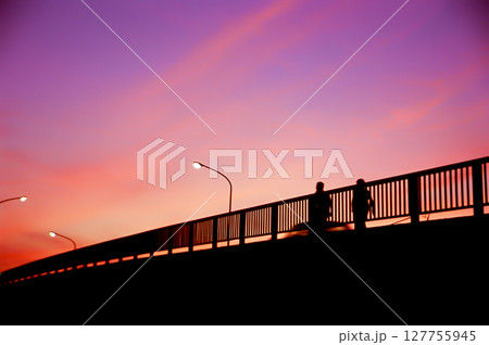 夕焼け空と歩道橋を歩く人々のシルエット 127755945