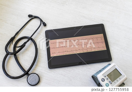 Table with phonendoscope, sphygmomanometer and myocardial infarction cardiogram on the tablet Table with phonendoscope, sphygmomanometer and myocardial infarction cardiogram on the tablet 127755958