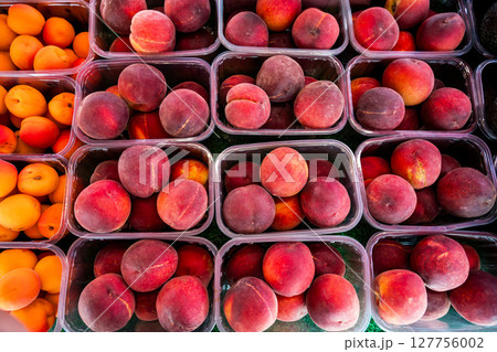 Peaches fruits in plastic containers, outdoor market display stall, top view 127756002