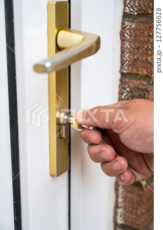 Man's hand locking the door, home safety or mortgage property concept 127756028