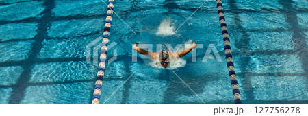 Swimmer executing butterfly stroke in competitive swimming pool lane Swimmer executing butterfly stroke in competitive swimming pool lane 127756278