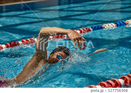 Man swimming freestyle stroke in outdoor swimming pool with lane dividers Man swimming freestyle stroke in outdoor swimming pool with lane dividers 127756308