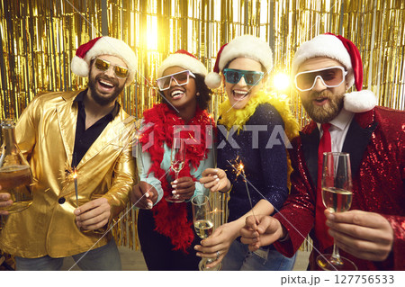 Happy people in party santa claus hat holding sparklers and champagne glasses Happy people in party santa claus hat holding sparklers and champagne glasses 127756533