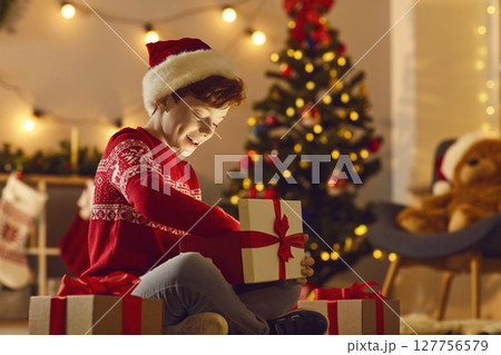 Happy excited boy opens a Christmas present and excitedly looks at the magic light in the box. 127756579