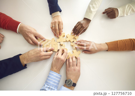 View from above of diverse business team putting together pieces of jigsaw puzzle View from above of diverse business team putting together pieces of jigsaw puzzle 127756710