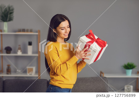 Charming woman holding present box with bow 127756899