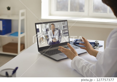 Professional doctor giving online consultation to patient via video call on laptop 127757377