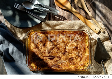 Glass platter with a meat or shepherd's pie on a rustic country table. 127757384