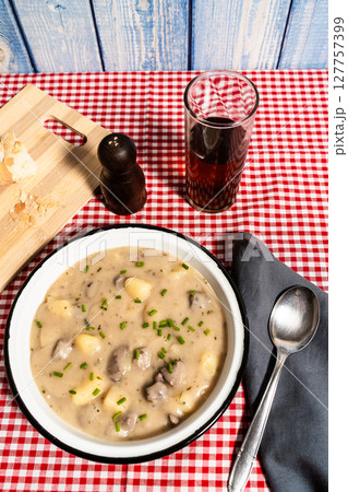 Creamy chicken gizzard and potato soup served on checkered tablecloth with bread and drink Creamy chicken gizzard and potato soup served on checkered tablecloth with bread and drink 127757399