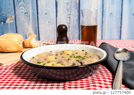 Traditional hungarian goulash soup served with bread and dark beer on a checkered tablecloth Traditional hungarian goulash soup served with bread and dark beer on a checkered tablecloth 127757400