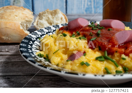 Creamy polenta topped with sausage, tomato sauce, and chives with crusty bread 127757421