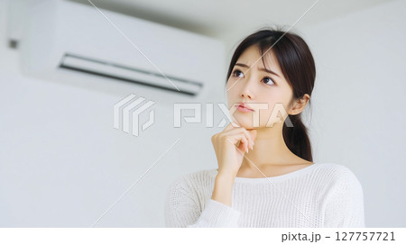 エアコンの故障で修理か買い替えかで悩む若い女性の表情 エアコンの故障で修理か買い替えかで悩む若い女性の表情 127757721