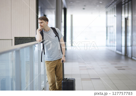 到着後にキャリーケースを引いて通路を進む男性旅行者 到着後にキャリーケースを引いて通路を進む男性旅行者 127757783