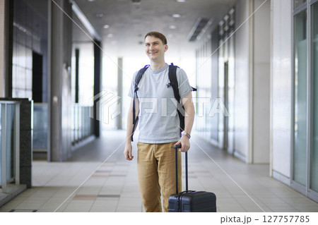 キャリーケースを引いて通路を進む男性旅行者 キャリーケースを引いて通路を進む男性旅行者 127757785