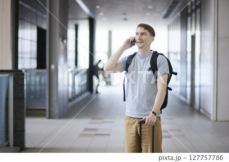 キャリーケースを引きながら電話する男性 キャリーケースを引きながら電話する男性 127757786