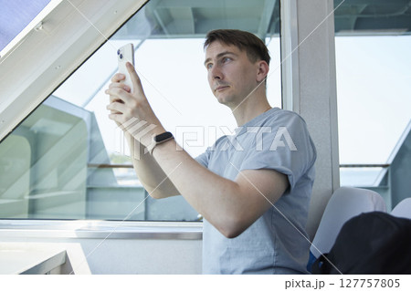 窓際でスマホ操作をする男性旅行者 127757805
