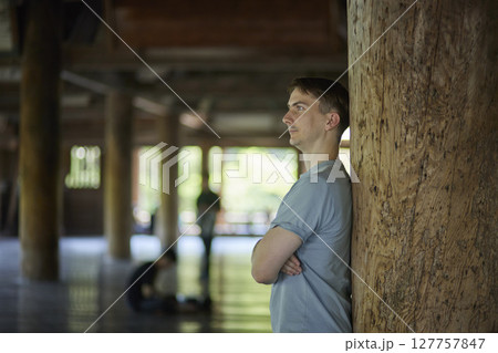 柱にもたれ掛かる男性旅行者のポートレート 127757847