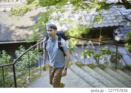 自然豊かな参道を登るバックパック姿の男性 127757856