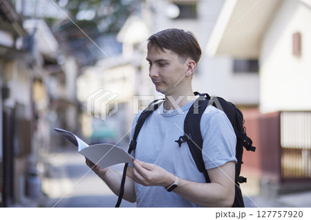 街角で観光ガイドを確認するバックパッカー 127757920