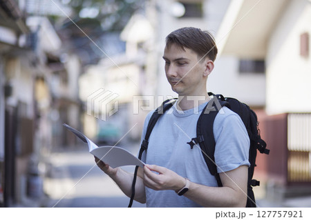 街角で観光ガイドを確認するバックパッカー 127757921