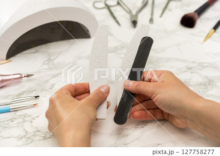 Gel nail manicure at home, female hands with nail files 127758277