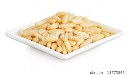 Shelled European pine nuts in ceramic bowl isolated on white background with full depth of field 127758484