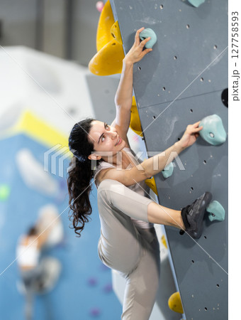 Young woman doing rock climbing on climbing wall 127758593